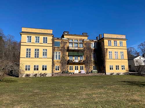 Ett stort gult hus framför en stor gräsplätt